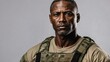 © Tom - Serious black middle-aged male soldier in military gear, camouflage, intense gaze, grey background