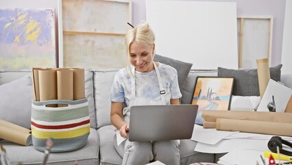 Poster - Vibrant, young blonde artist, sipping coffee during engaging art class video call in her bustling studio