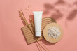 Rice bran powder is displayed on a round wooden podium. An unlabeled white tube and rice are placed on a dome-shaped platform on a pink background. Cosmetic ads with natural ingredients.