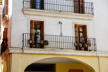 Decorative balconies and windows with gates of old city center house in Seville, Spain