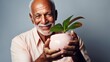 © Z A C - A happy elderly man holds a pot of greenery in his hands, showcasing diversity.