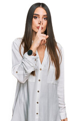 Wall Mural - Young beautiful woman wearing casual white shirt asking to be quiet with finger on lips. silence and secret concept.