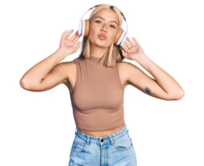 Sticker - Beautiful young blonde woman listening to music using headphones looking at the camera blowing a kiss being lovely and sexy. love expression.