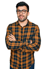 Wall Mural - Hispanic man with beard wearing casual clothes and glasses happy face smiling with crossed arms looking at the camera. positive person.