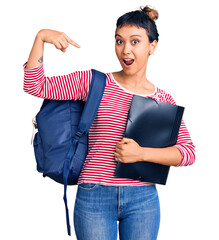 Poster - Young woman wearing student backpack holding binder smiling happy pointing with hand and finger