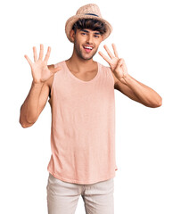 Wall Mural - Young hispanic man wearing summer hat showing and pointing up with fingers number eight while smiling confident and happy.