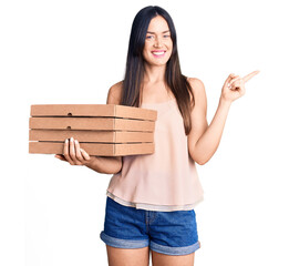 Canvas Print - Young beautiful caucasian woman holding delivery pizza box smiling happy pointing with hand and finger to the side