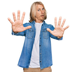 Poster - Caucasian man with blond long hair wearing casual denim jacket doing stop gesture with hands palms, angry and frustration expression