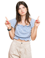 Canvas Print - Young beautiful caucasian girl wearing casual clothes pointing up looking sad and upset, indicating direction with fingers, unhappy and depressed.