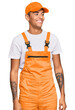 © Krakenimages.com - Young handsome african american man wearing handyman uniform looking away to side with smile on face, natural expression. laughing confident.
