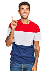 Sticker - Young handsome african american man wearing casual clothes showing and pointing up with finger number one while smiling confident and happy.