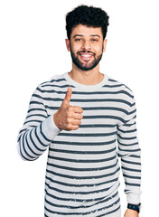 Poster - Young arab man with beard wearing casual striped sweater doing happy thumbs up gesture with hand. approving expression looking at the camera showing success.