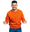 © Krakenimages.com - Young hispanic man with beard wearing casual orange sweater very happy and excited doing winner gesture with arms raised, smiling and screaming for success. celebration concept.