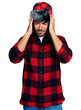 Hispanic young man with beard wearing fluffy earmuff hat with hand on head for pain in head because stress. suffering migraine.