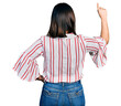 © Krakenimages.com - Young hispanic girl wearing casual clothes posing backwards pointing ahead with finger hand