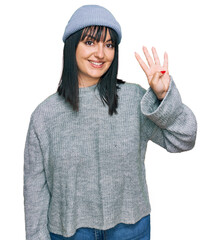 Canvas Print - Young hispanic woman wearing cute wool cap showing and pointing up with fingers number four while smiling confident and happy.