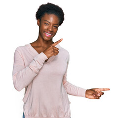 Wall Mural - Young african american girl wearing casual clothes smiling and looking at the camera pointing with two hands and fingers to the side.