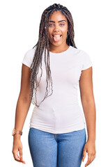 Wall Mural - Young african american woman with braids wearing casual clothes sticking tongue out happy with funny expression. emotion concept.