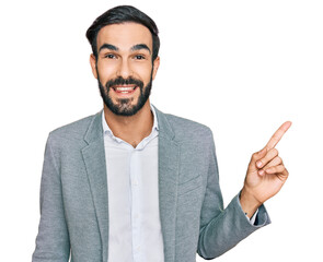 Sticker - Young hispanic man wearing business clothes with a big smile on face, pointing with hand finger to the side looking at the camera.