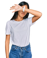 Poster - Beautiful young asian woman wearing casual white t shirt covering eyes with arm, looking serious and sad. sightless, hiding and rejection concept