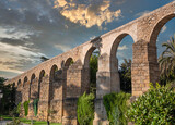 Fototapeta  - Vista de los pilares y arcos del histórico acueducto romano en la villa de Plasencia, España, con cielo editado