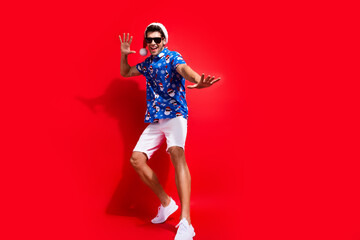 Wall Mural - Full length photo of nice young male dance have fun discotheque dressed santa claus print x-mas garment isolated on red color background