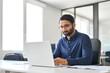 © insta_photos - Busy serious professional Indian business man company employee, male worker, manager or financial analyst typing on computer technology using laptop working with ai solutions sitting at office desk.