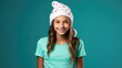 Christmas, smiling young girl in Santa helper hat, wearing aqua color clothes
