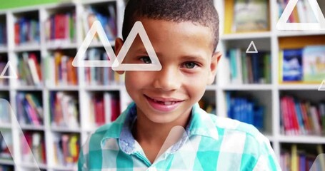 Sticker - Animation of triangles over close up of smiling biracial boy standing in library room