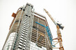 FRANKFURT, GERMANY - July 19, 2023: Building a skyscraper with a crane. Construction of high-rise building on the background of cloudy sky.