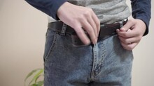 A Guy Puts On A Belt On His Jeans, A Young Man Puts A Leather Belt On His Trousers