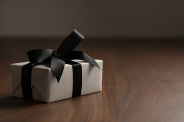 Wall Mural - White paper gift box with black ribbon on walnut wood table with copy space