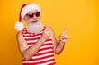 Photo of impressed funky senior guy dressed christmas swimwear hat pointing two fingers empty space isolated yellow color background