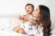 © Art_Photo - Portrait of enjoy happy love family asian mother playing with adorable little asian baby, newborn, infant.Mom touching care with cute son in a white bedroom.Love of family concept