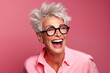 Femme senior, heureuse et souriante portant des lunettes, arrière-plan isolé de couleur rose.