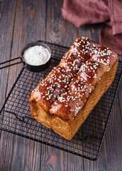 Wall Mural - Butter brioche bread sprinkled with pearl sugar on black grille on a dark wooden background.  Wheat bread recipes.