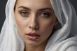 © liliyabatyrova - Close-up portrait of a beautiful Arab Muslim woman wearing a white headscarf, hijab and looking directly into the camera on a gray background.