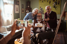 Senior Man In Wheelchair Celebrating Birthday With Friends At Home