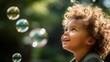 Kleiner farbiger Junge schaut staunend auf Seifenblasen