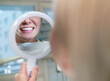 © Soloviova Liudmyla - Young smiling woman sitting in stomatology clinic chair and looked at mirror evaluating her teeth reflection after Tooth whitening procedure. Health care and medcare industry concept image