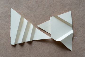 two paper shapes with fan fold elements on plain brown paper