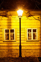 Canvas Print - An old wooden cottage illuminated at night by the light of a traditional lantern.