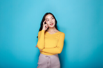 Portrait of a beautiful young woman in a light blue background, happy and smile, posting in stand position, Pretty girl makes a thoughtful expression.