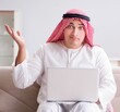 © Elnur - Young arab businessman working with laptop on sofa