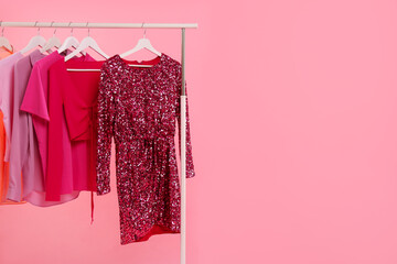 Wall Mural - Rack with different stylish women`s clothes on pink background, space for text