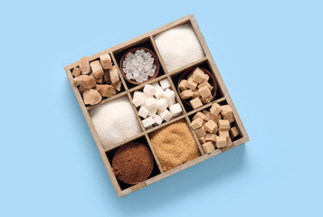 Wall Mural - Wooden box with different types of sugar on blue background
