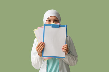 Sticker - Female Muslim doctor in hijab with clipboards on green background. World Hijab Day concept