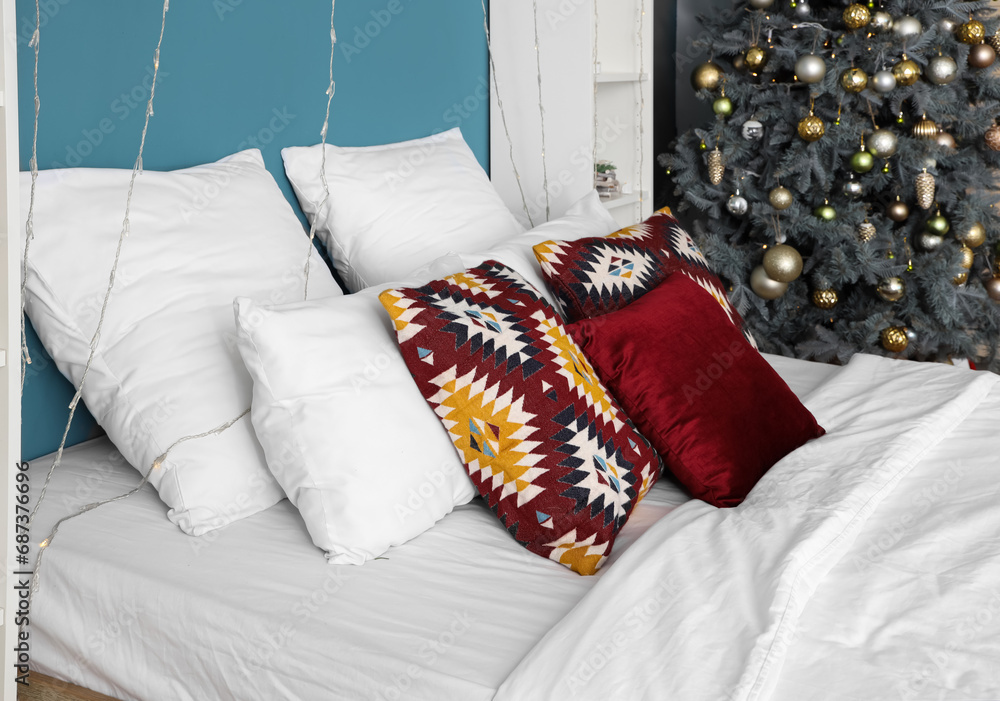 Big bed with pillows and Christmas lights in bedroom