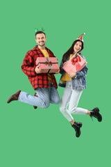 Poster - Young couple with Christmas presents jumping on green background