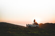 Group of travelers tourist stand by 4wd vehicle together in nature on adventure watch sunset over horizon over cloudscape in wilderness. Exploration and adventure
